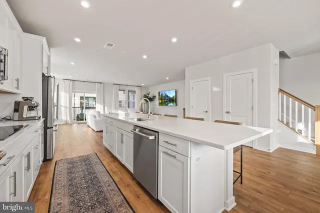 a large kitchen with stainless steel appliances a white stove top oven and white cabinets next to a window