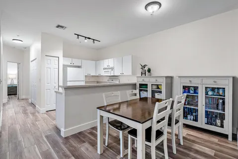 a kitchen with kitchen island a dining table chairs and white cabinets