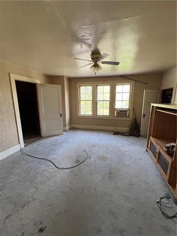 a view of an empty room with furniture and a ceiling fan