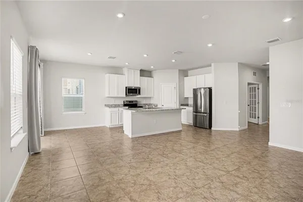 a view of kitchen with stainless steel appliances kitchen island granite countertop a refrigerator and a stove top oven
