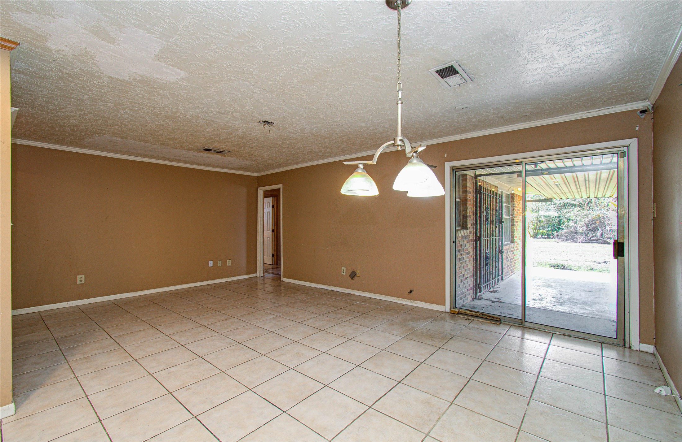 8428 Swiftwater Lane Houston, TX 77075 - Photo 10 of 26 Spacious room features tiled flooring, neutral wall colors, and a sliding glass door leading to a covered patio area, offering a seamless indoor-outdoor living experience.