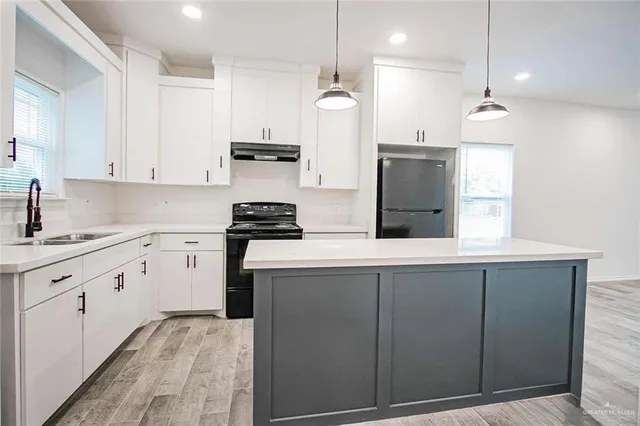 a kitchen with kitchen island white cabinets and refrigerator