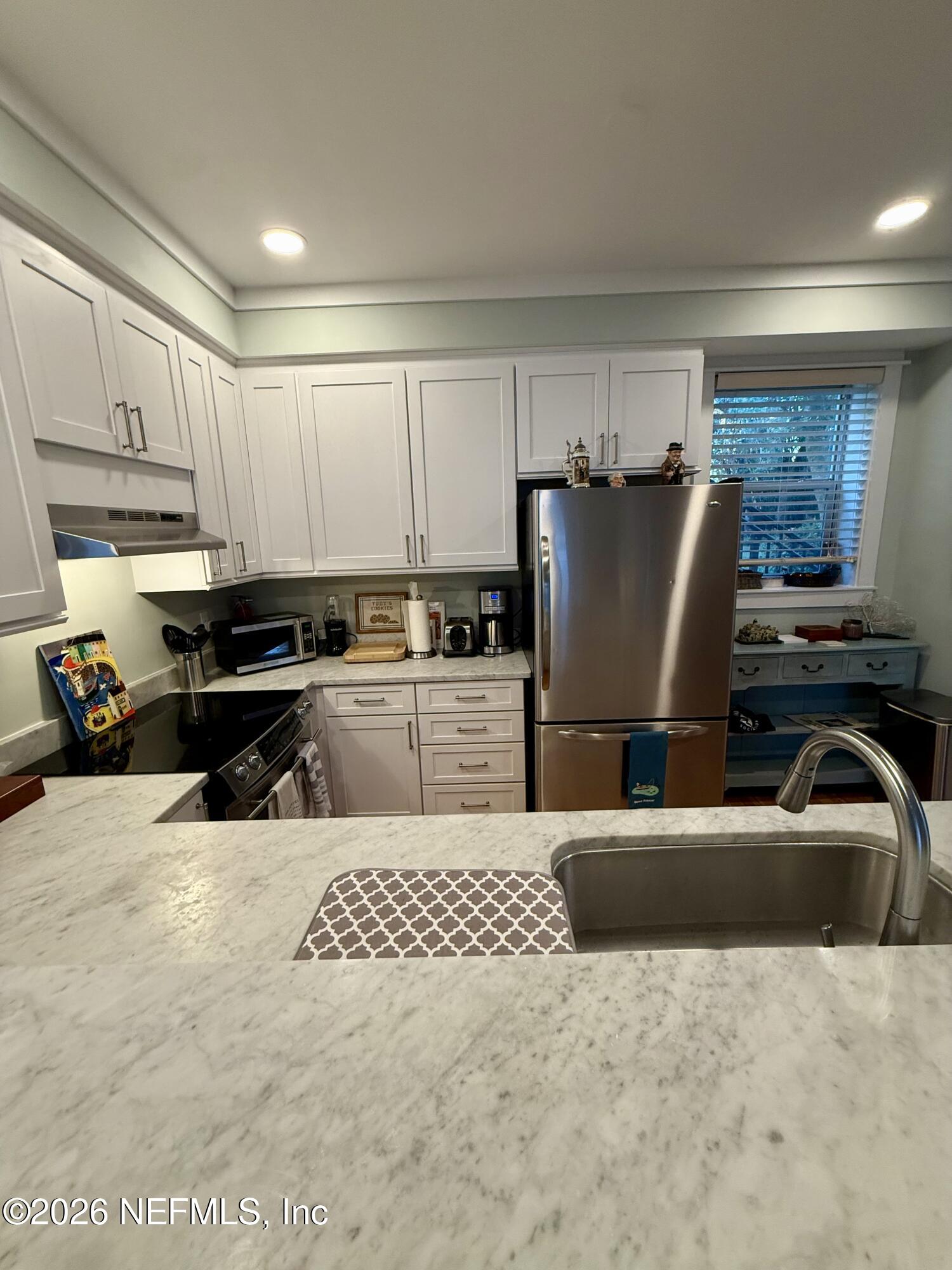 359 Ahern Street Atlantic Beach, FL 32233 - Photo 6 of 15 a kitchen with kitchen island granite countertop a refrigerator a stove a sink dishwasher and white cabinets with wooden floor