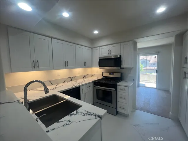 a kitchen with kitchen island stainless steel appliances a sink stove and refrigerator