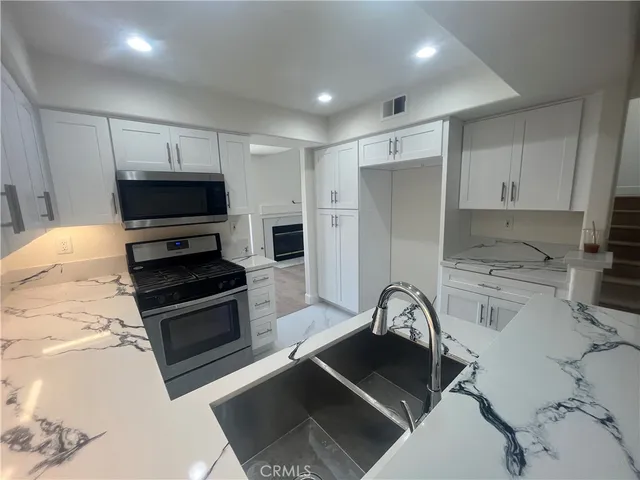 a kitchen with stainless steel appliances a stove a sink and a microwave