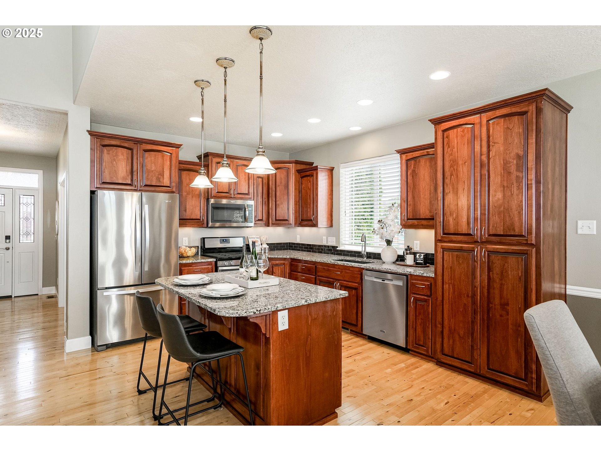 413 Northwest Harold Street Sublimity, OR 97385 - Photo 16 of 48 a kitchen with stainless steel appliances granite countertop a refrigerator a sink dishwasher a dining table and chairs with wooden floor