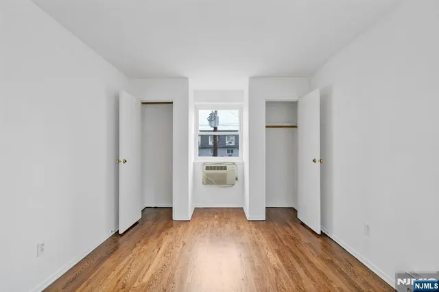 a view of a hallway with wooden floor and a kitchen