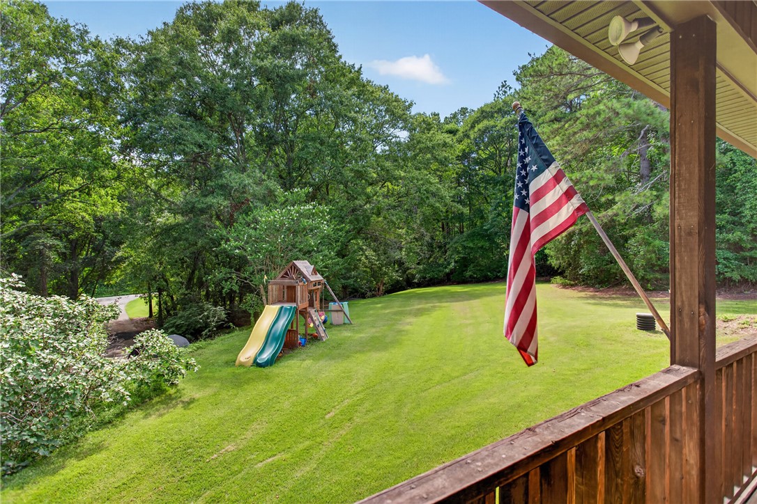 120 Coneross Knob Drive Seneca, SC 29678 - Photo 19 of 37 The front porch offers a a view of the front yard featuring a vibrant playground and lush green lawn, bordered by dense natural landscaping.