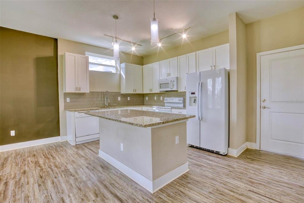 1801 Houston Street Kissimmee, FL 34743 - Photo 11 of 32 a kitchen with kitchen island granite countertop a sink cabinets and wooden floor