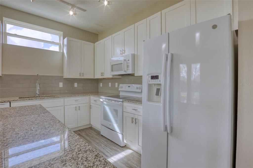 1801 Houston Street Kissimmee, FL 34743 - Photo 13 of 32 a kitchen with stainless steel appliances granite countertop a refrigerator and a sink