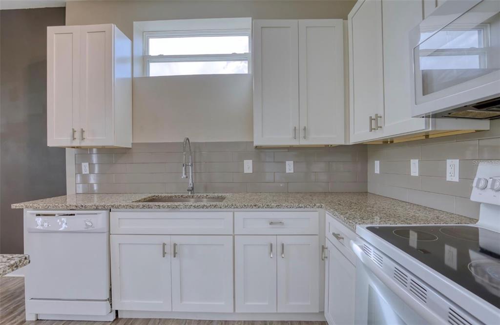 1801 Houston Street Kissimmee, FL 34743 - Photo 14 of 32 a kitchen with stainless steel appliances granite countertop a sink a stove and white cabinets