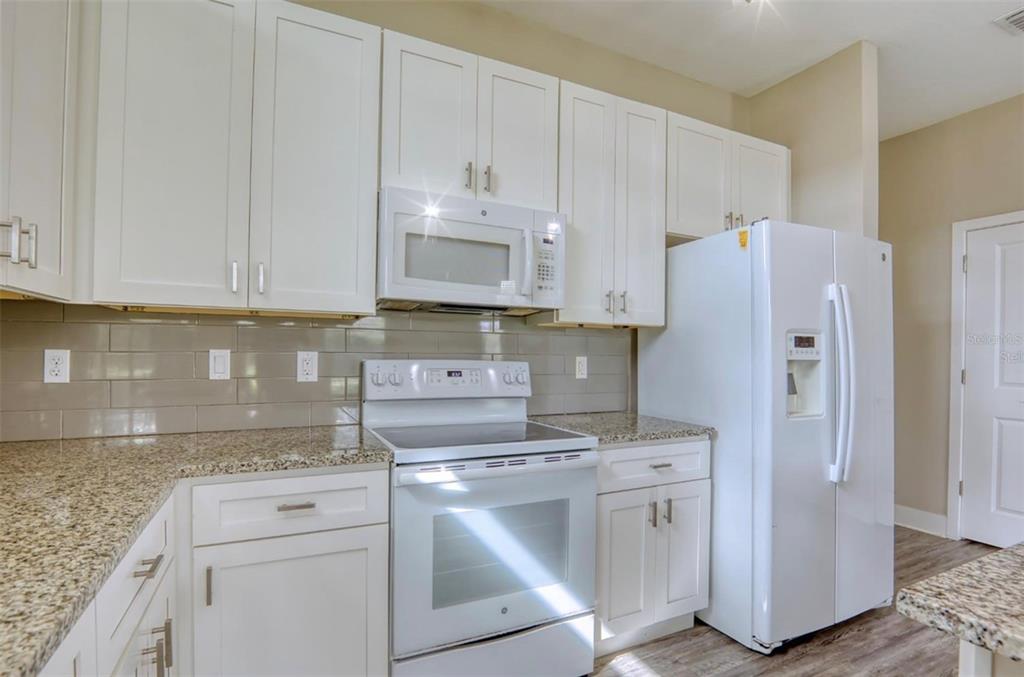 1801 Houston Street Kissimmee, FL 34743 - Photo 15 of 32 a kitchen with white cabinets and white appliances