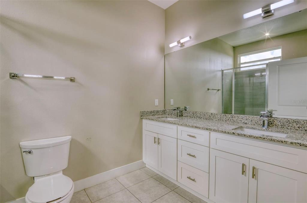 1801 Houston Street Kissimmee, FL 34743 - Photo 20 of 32 a bathroom with a granite countertop toilet sink and mirror