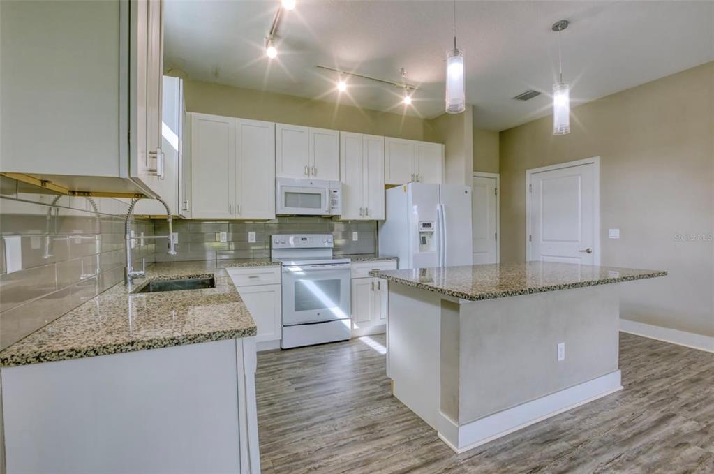 1801 Houston Street Kissimmee, FL 34743 - Photo 9 of 32 a kitchen with stainless steel appliances granite countertop wooden cabinets and a granite counter tops