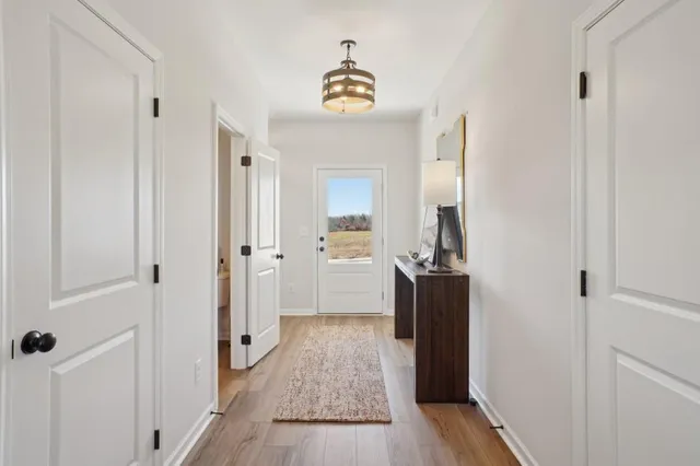 a view of a hallway view with wooden floor and a bathroom