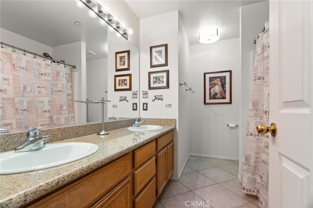 944 Riverview Drive Redlands, CA 92374 - Photo 20 of 32 a bathroom with a granite countertop sink a mirror a vanity and a shower