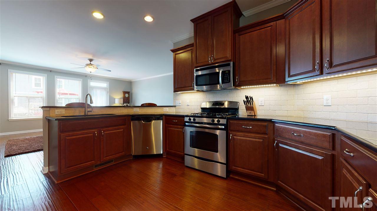 1329 Rembrandt Circle Raleigh, NC 27607 - Photo 8 of 23 a kitchen with stainless steel appliances granite countertop wooden cabinets a stove a sink and dishwasher with wooden floor