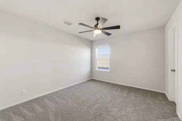 an empty room with a window and a ceiling fan