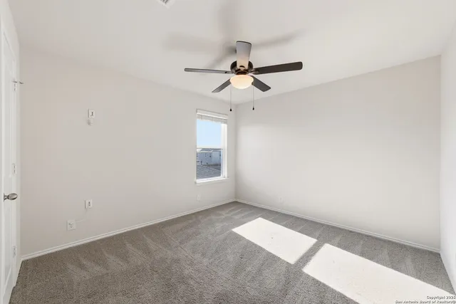 an empty room with windows and chandelier fan