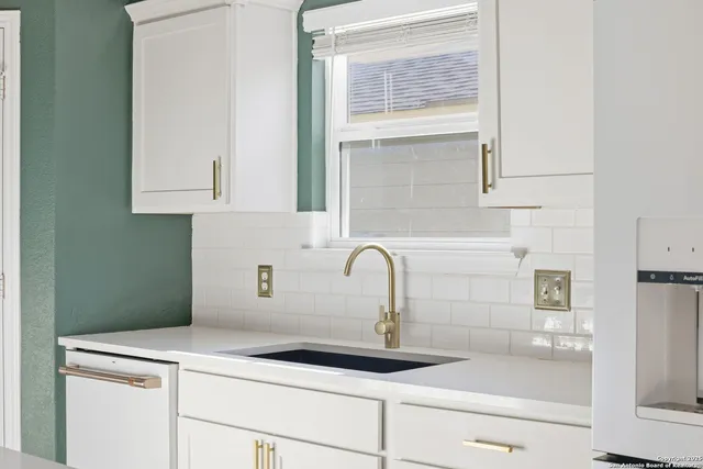 a kitchen with granite countertop white cabinets and stainless steel appliances