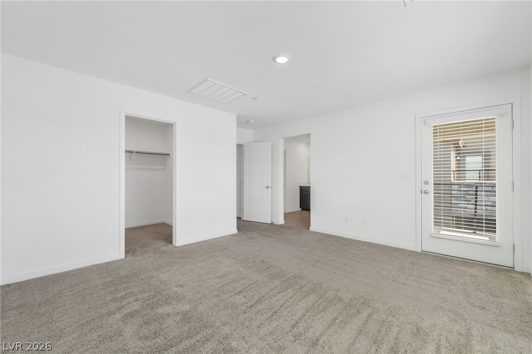 894 Cadence View Way Henderson, NV 89011 - Photo 15 of 23 A spacious primary bedroom featuring plush gray carpeting and a private balcony access.