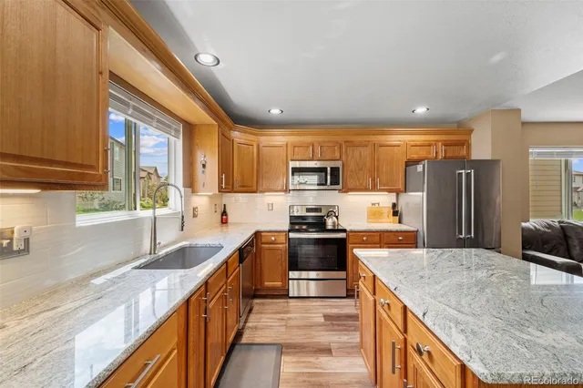 a kitchen with stainless steel appliances granite countertop a sink a stove and a refrigerator