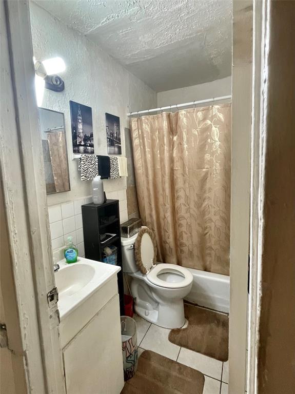 3525 Colonial Avenue Dallas, TX 75215 - Photo 5 of 24 Bathroom with vanity, a textured wall, tile patterned flooring, tile walls, and shower / bath combo with shower curtain