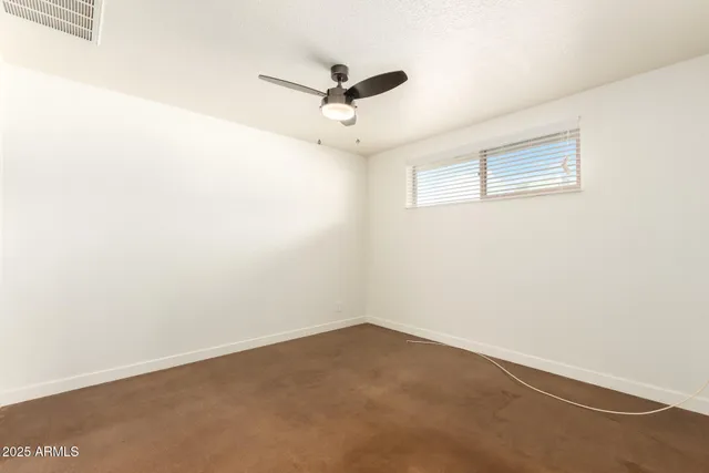 an empty room with a ceiling fan and window