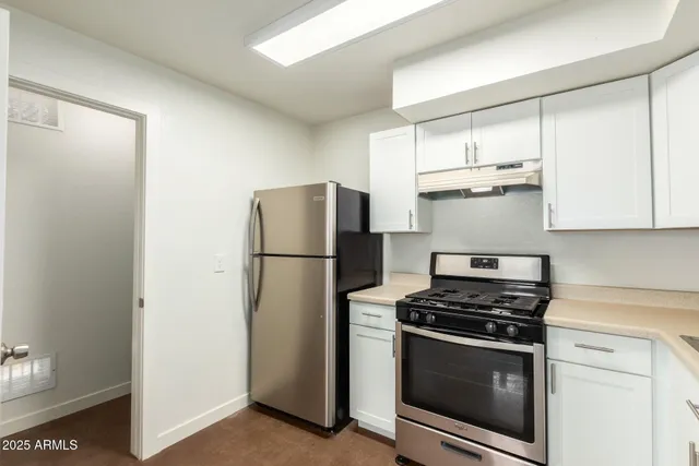 a kitchen with stainless steel appliances a refrigerator a stove and white cabinets