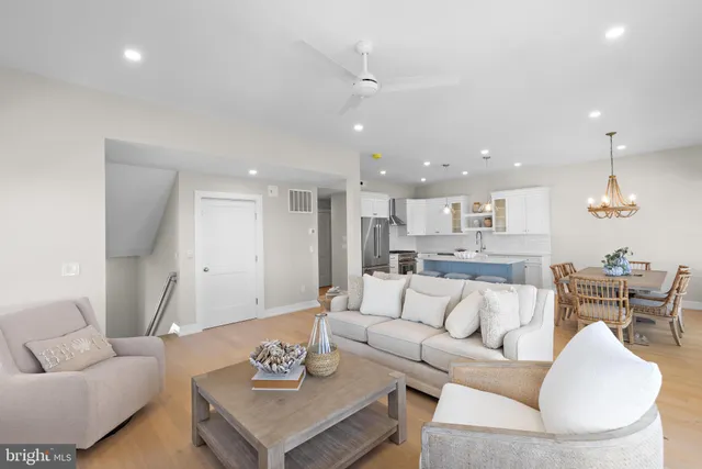 a living room with furniture kitchen view and a chandelier