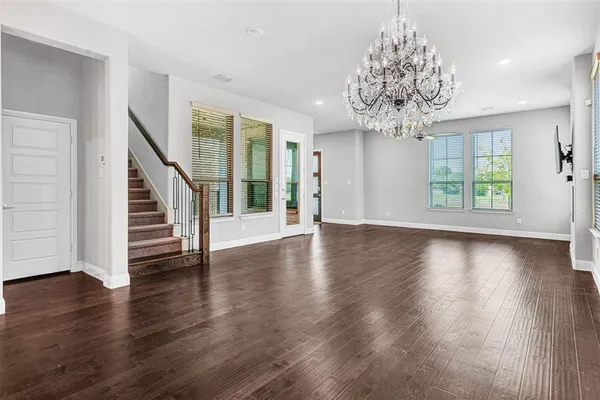 a view of a room with wooden floor chandelier and windows
