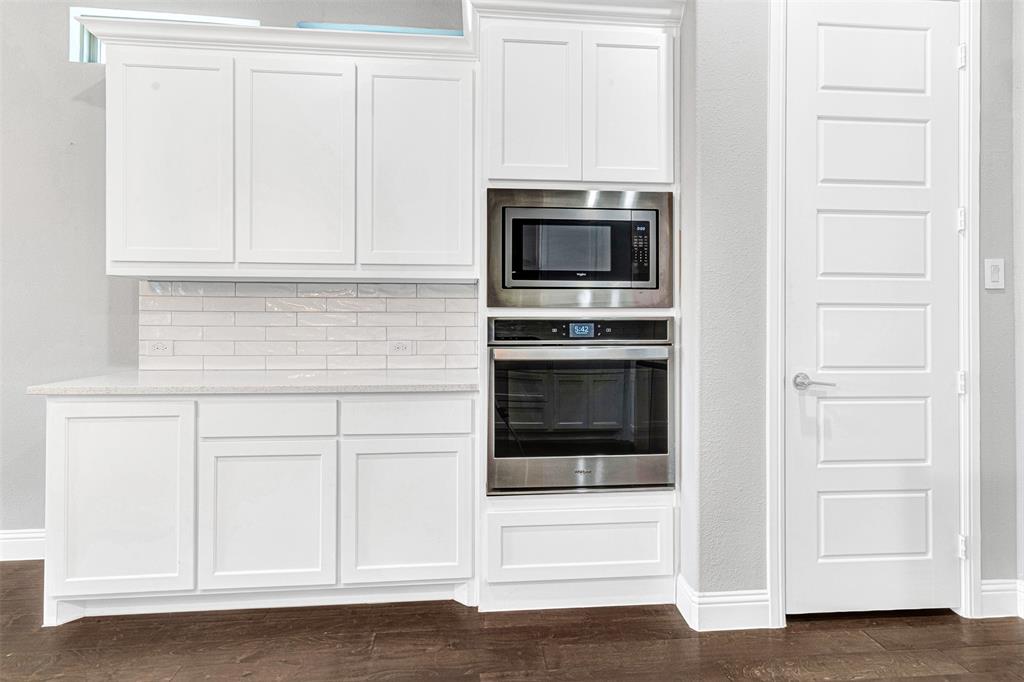 468 Caitlyn Way Fairview, TX 75069 - Photo 14 of 35 Kitchen with stainless steel appliances, white cabinets, light stone counters, and dark wood-style flooring