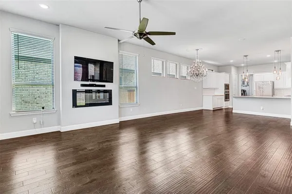 a view of a kitchen with furniture a ceiling fan and wooden floor