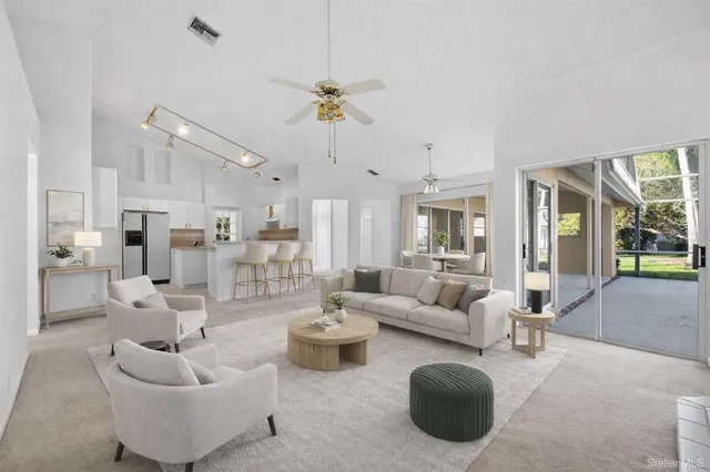 a living room with furniture kitchen view and a chandelier