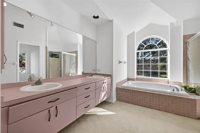 a bathroom with a double vanity sink bathtub and window