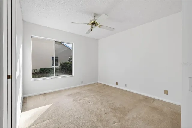 an empty room with a ceiling fan and a window