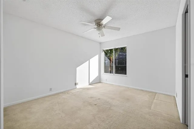 an empty room with a ceiling fan and window