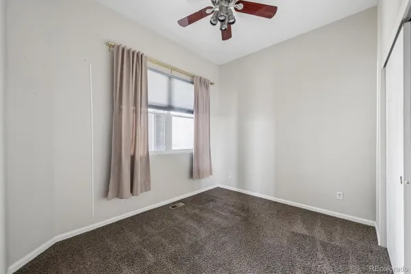 an empty room with windows and ceiling fan