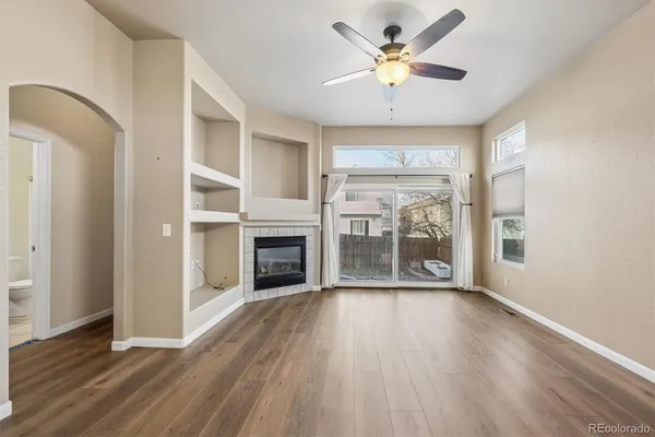 an empty room with wooden floor a ceiling fan and windows