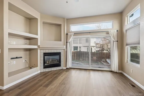 a view of a livingroom with wooden floor and a fireplace
