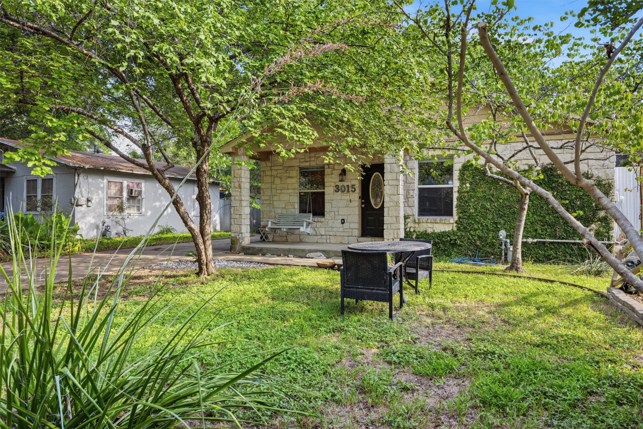 3015 Castro Street Austin, TX 78702 - Photo 3 of 40 A charming stone facade invites, shaded by mature trees with a welcoming front porch swing.