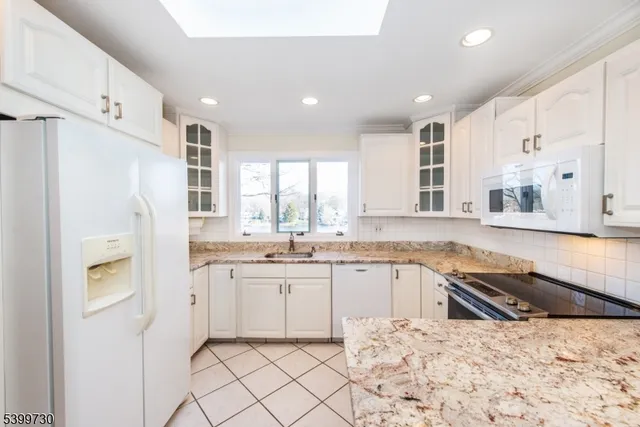 a kitchen with granite countertop a sink and white cabinets