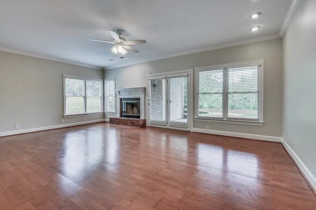 an empty room with wooden floor fireplace and windows
