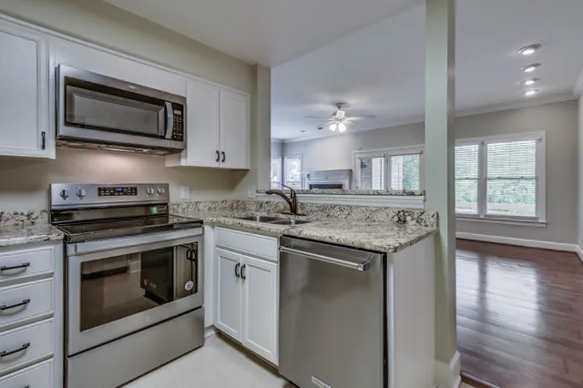 a kitchen with stainless steel appliances white cabinets and a stove a refrigerator with wooden floor