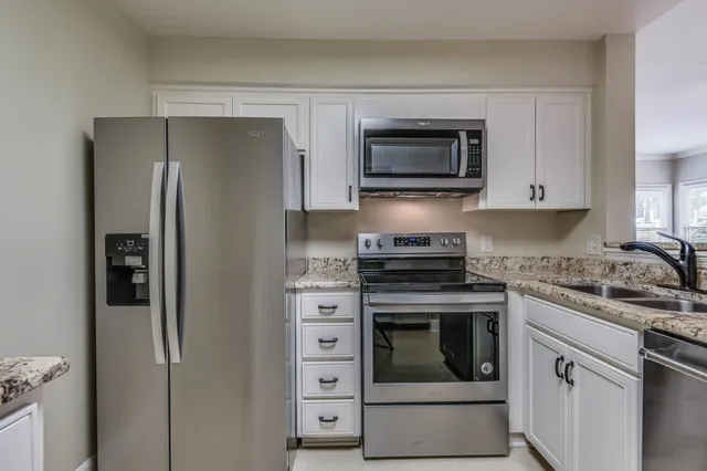 a kitchen with granite countertop white cabinets and white appliances