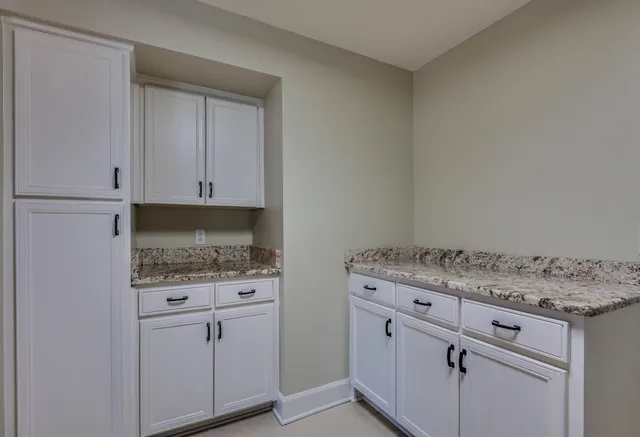 an empty room with chandelier fan and windows