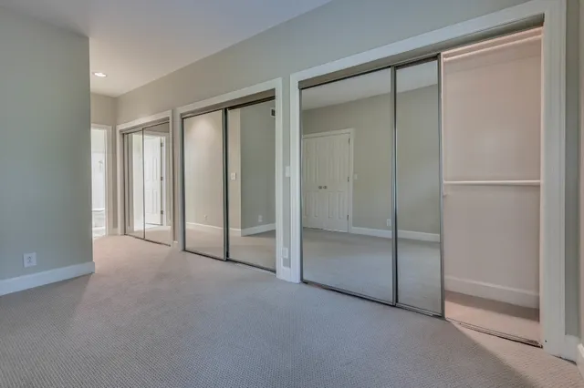 an empty room with chandelier fan and windows