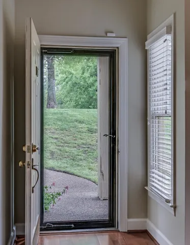 an empty room with wooden floor chandelier and windows