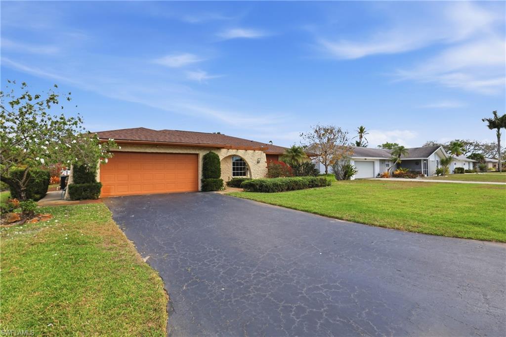 135 Pebble Beach Boulevard Naples, FL 34113 - Photo 2 of 37 a front view of a house with a yard and garage