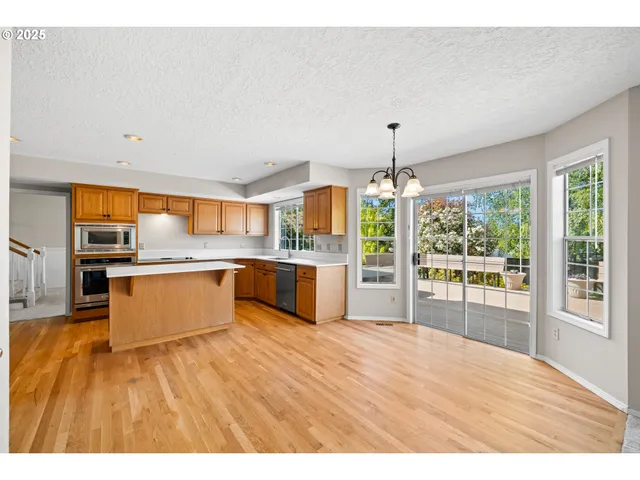 a large kitchen with kitchen island a large counter top space a sink stainless steel appliances and cabinets
